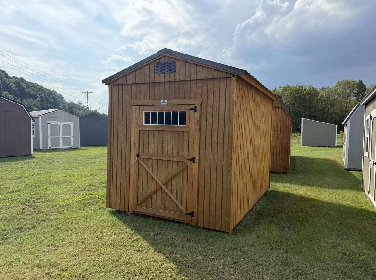 eight by 12 utility shed outside shot, with wooden paneling outside and brown roof