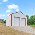 Custom-built white metal pole barn garage with red trim and dual overhead doors, measuring thirty by thirty feet with twelve-foot walls, constructed on a four-inch concrete pad—perfect for post frame buildings, residential storage, workshops, or vehicle parking.