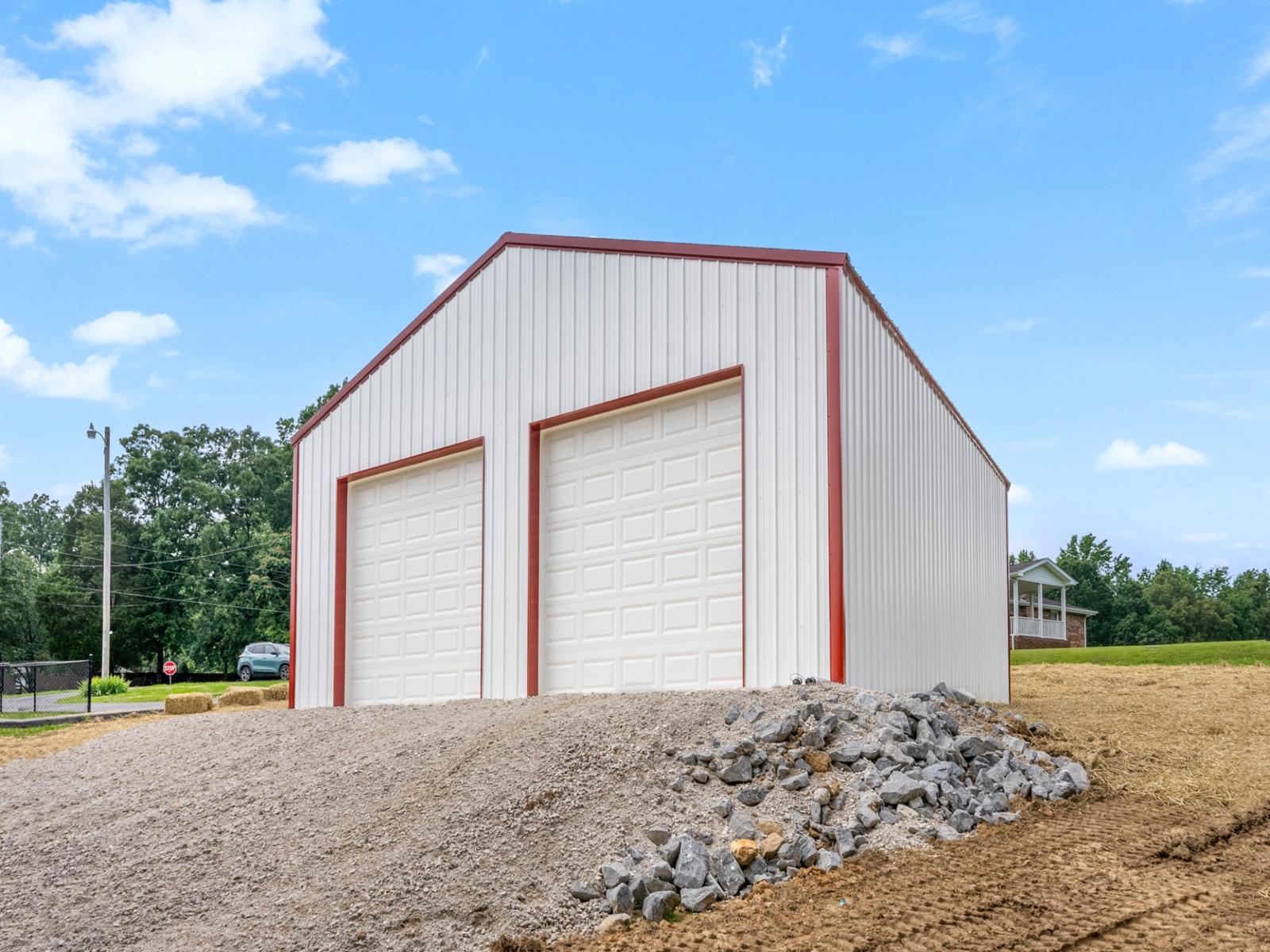 Custom-built white metal pole barn garage with red trim and dual overhead doors, measuring thirty by thirty feet with twelve-foot walls, constructed on a four-inch concrete pad—perfect for post frame buildings, residential storage, workshops, or vehicle parking.