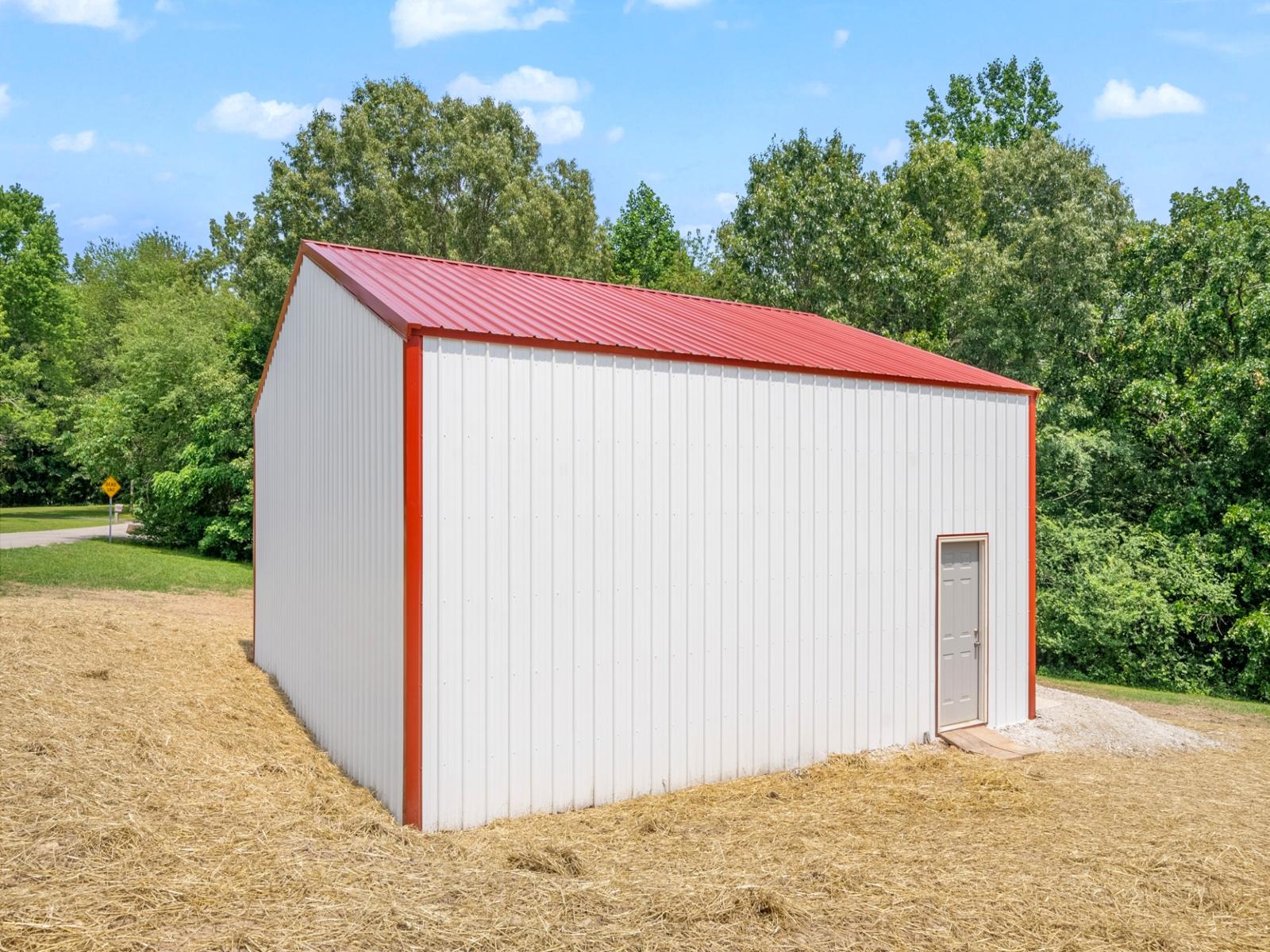 Custom-built white metal pole barn garage with red trim and dual overhead doors, measuring thirty by thirty feet with twelve-foot walls, constructed on a four-inch concrete pad—perfect for post frame buildings, residential storage, workshops, or vehicle parking.