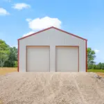 Custom-built white metal pole barn garage with red trim and dual overhead doors, measuring thirty by thirty feet with twelve-foot walls, constructed on a four-inch concrete pad—perfect for post frame buildings, residential storage, workshops, or vehicle parking.